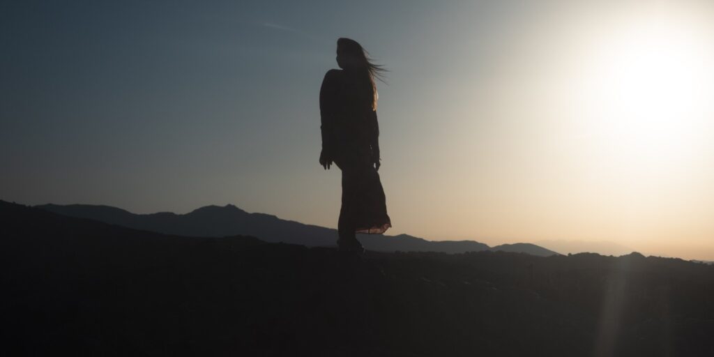 Silueta de Clara de perfil ante un paisaje al atardecer.